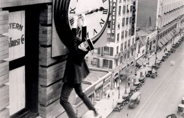 Harold Lloyd hanging from a large clock face above a city street