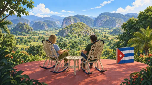 Two travellers in rocking chairs overlooking the green Viñales valley, beside a wooden Cuban flag.