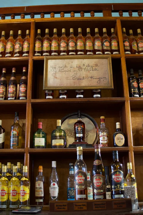 Wooden shelves filled with rum bottles and a framed handwritten note