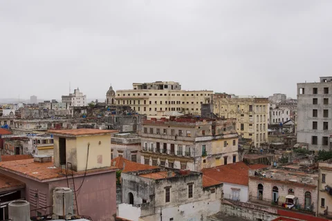 Weathered buildings and red-tiled rooftops stretching across Havana under a grey sky
