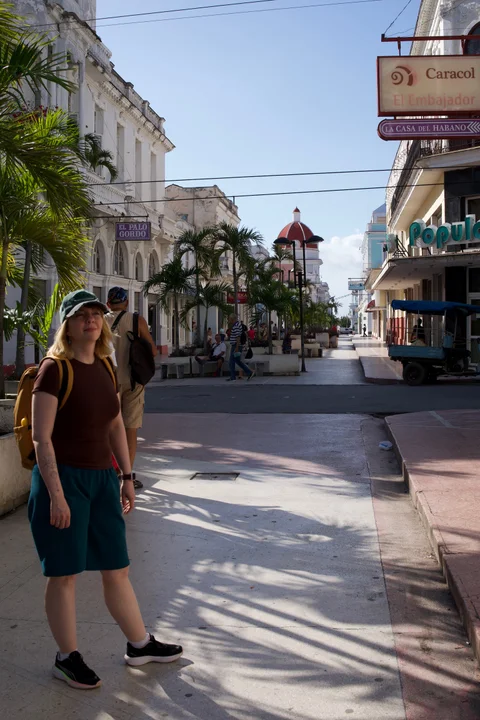 Lena with a yellow backpack on a palm-lined pedestrian street in Cienfuegos