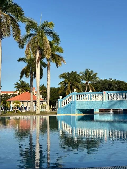 A blue bridge and tall palm trees reflected in the hotel swimming pool in Varadero