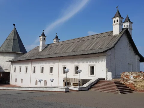 A long white building with steep roofs, small turrets, and an outside staircase.