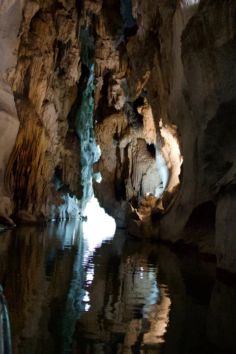Tall rock formations reflected in the water inside the cave