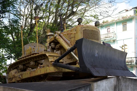 A weathered yellow bulldozer on display at the Tren Blindado monument in Santa Clara