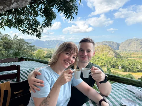 Lena and me raising white coffee cups, with the Viñales valley behind us