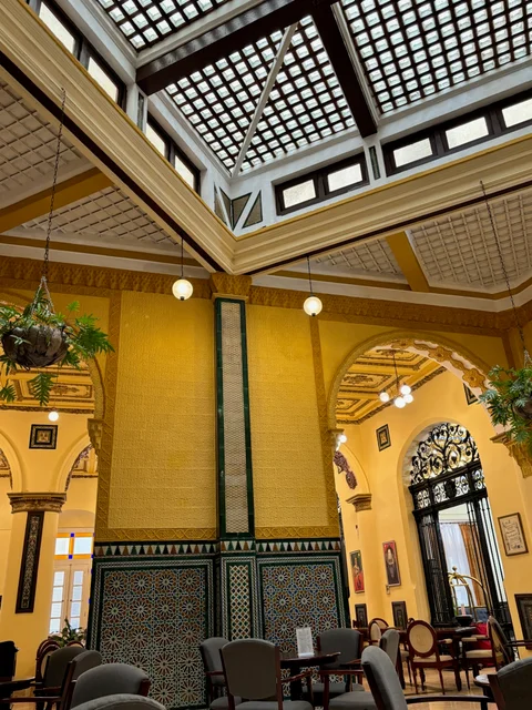 Yellow arches, patterned tiles and hanging plants beneath the glass ceiling at Hotel Inglaterra