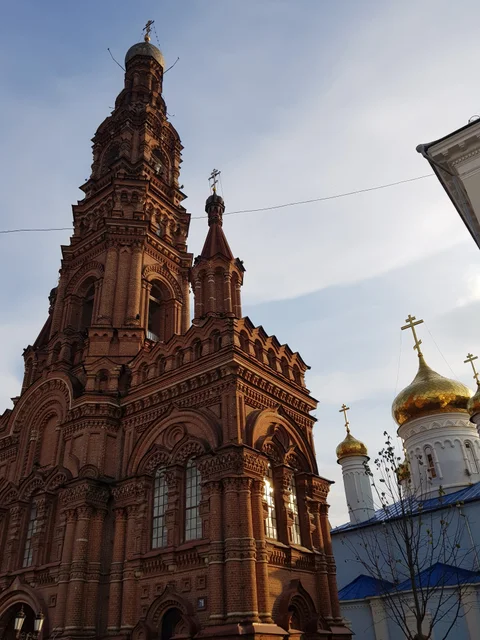 Looking up past the red-brick bell tower towards a white church and its gold dome.