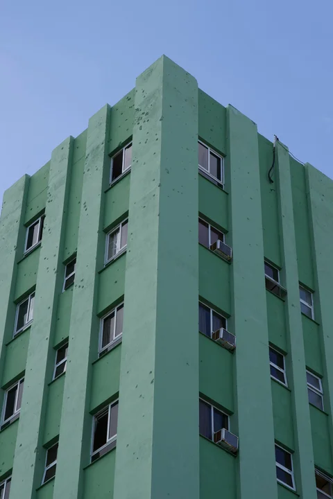 The green facade of the Santa Clara Libre hotel, with small marks in the plaster and rows of windows