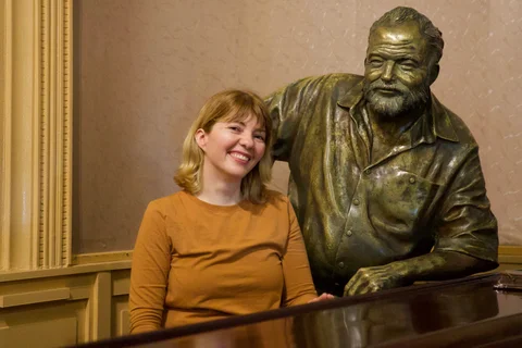 Lena smiling beside the bronze statue of Hemingway at the bar in Floridita