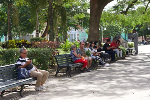 People sitting on shaded benches beneath trees in Parque Vidal, Santa Clara