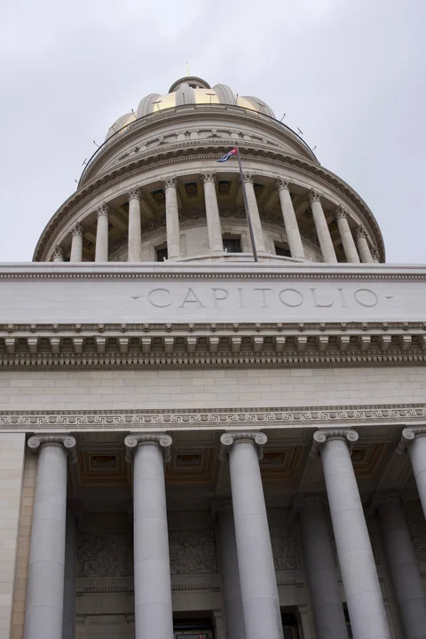 The Capitol’s white columns, carved name and dome with a Cuban flag, seen from below