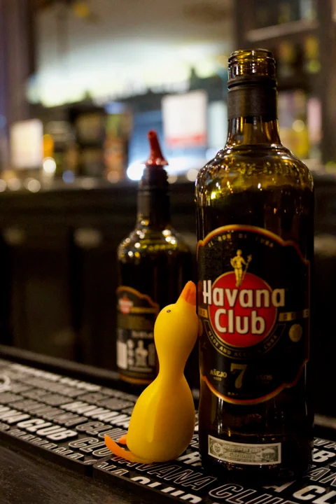 Our mascot, a yellow toy duck, beside a bottle of Havana Club 7 on the bar counter