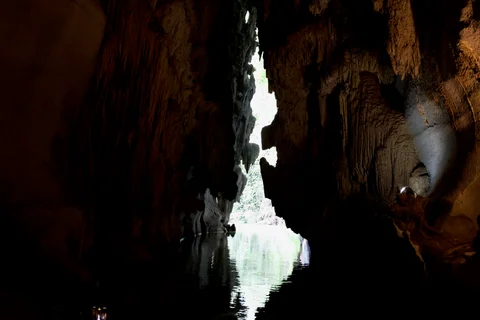Daylight reflected in the water between the dark rock walls at the cave opening