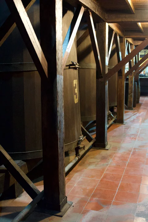 Large wooden vats supported by timber beams beside a tiled walkway at Havana Club