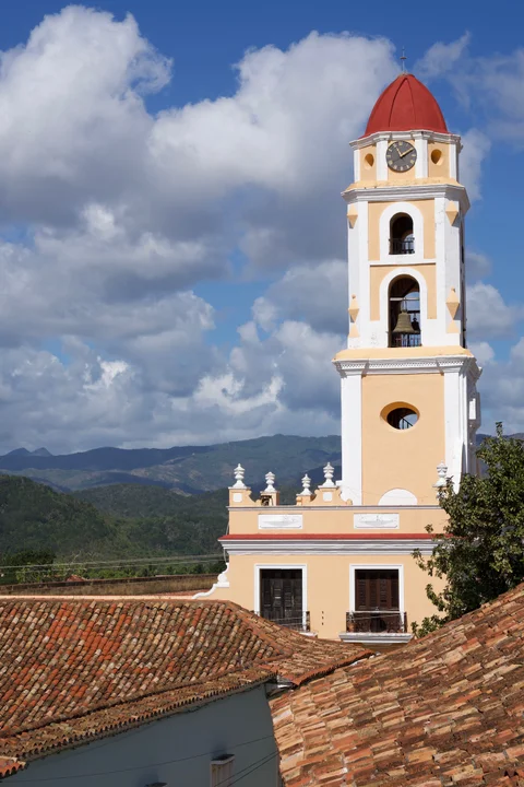 The yellow and white San Francisco bell tower with its red dome above the tiled rooftops of Trinidad