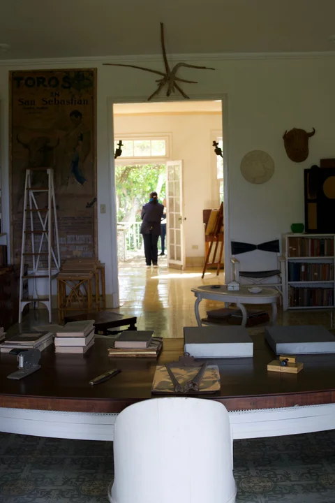 Books and a bullfighting poster inside Finca Vigía, with a view through the rooms to an open door