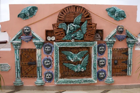 Green cherubs and lion faces decorating wooden shutters on a peach-coloured wall