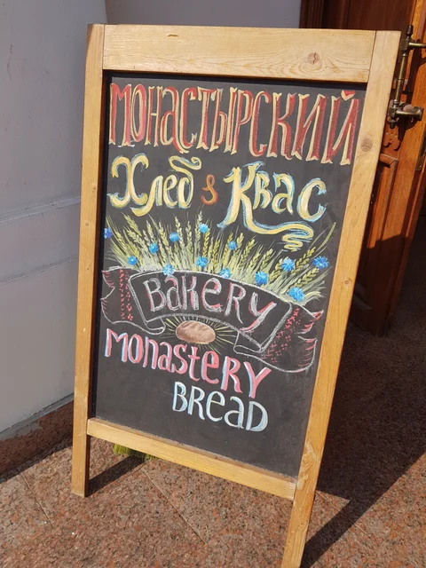 A hand-lettered chalkboard advertises kvass and monastery bread.