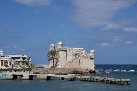 The Torreón de Cojímar beside the sea, with a low concrete pier stretching across the water