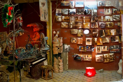 Photographs hanging in rows beside sculptures and a piano inside a Havana workshop