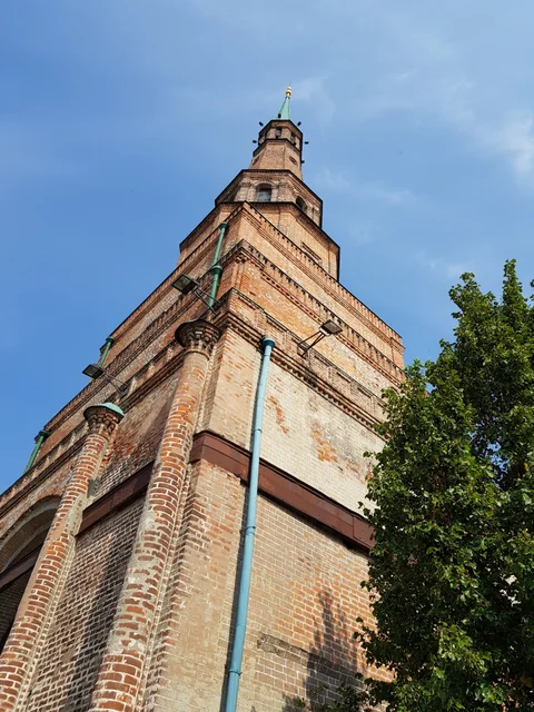 A metal downpipe runs up the red-brick wall of the Syuyumbike Tower.