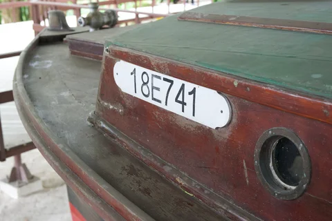 The wooden cabin and round porthole of Pilar, with its registration number on a white plate