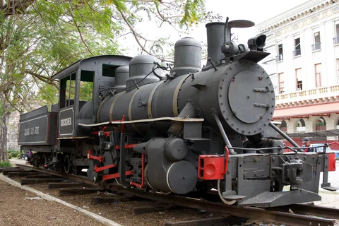 A black steam locomotive with red details on a short display track in Havana