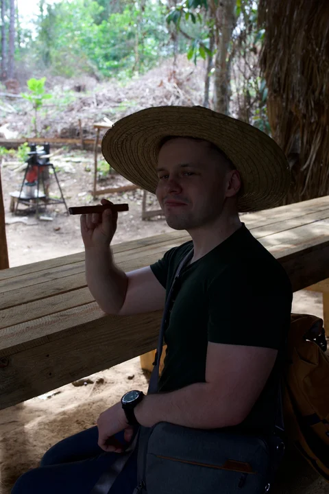 Me in a straw hat, holding a cigar and looking at the camera at the tobacco farm