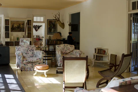 Floral armchairs, bookshelves, paintings and hunting trophies in the living room at Finca Vigía