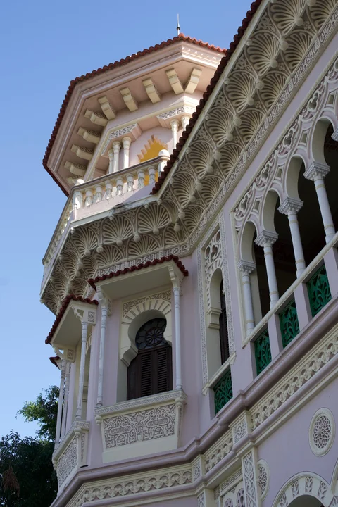 The ornate pink and cream facade of Palacio de Valle in Punta Gorda, Cienfuegos, with arches and green railings