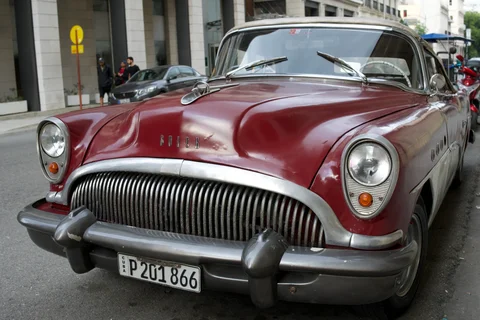 A red and cream Buick with a wide chrome grille parked on a Havana street