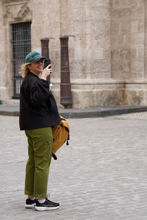 Lena, my beautiful wife, smiling as she takes a photograph in her green cap on a Havana street