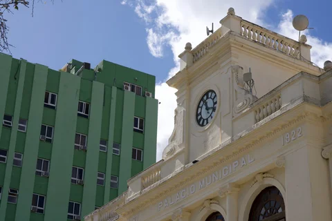 The clock and pale facade of the Palacio Municipal beside the green Santa Clara Libre hotel