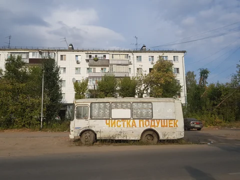 A parked van advertising pillow cleaning beside a block of flats.