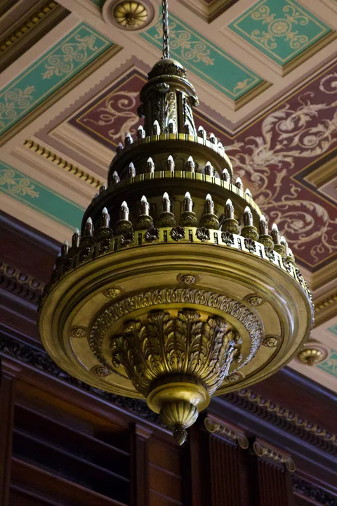 A tiered chandelier beneath turquoise and purple ceiling panels inside the Capitol