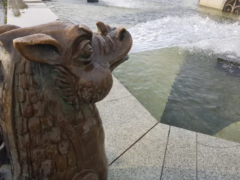 A dragon’s head at the edge of a fountain, with water churning behind it.
