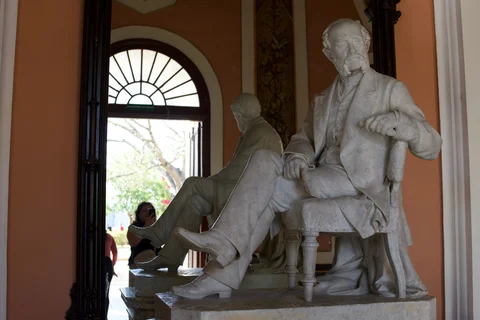 A seated marble statue of Tomás Terry in the theatre foyer, reflected in a tall mirror